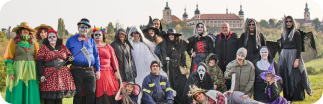 Group of people dressed as fairytale creatures standing in front of old castle