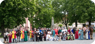 Group of people with cowboy costumes on, taking a picture near old church and trees
